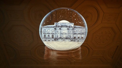 A light projection of a grand house shines on an ornate ceiling